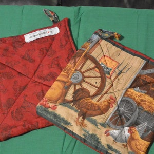 May include: Two red and white quilted pot holders. One features a rooster and wagon design, the other a rooster and chicken design. Both have the text "Handmade with Love" on them.