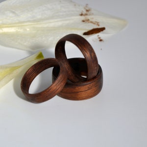 Peut inclure: Trois anneaux en bois empilés les uns sur les autres. Les anneaux sont de couleur brun foncé et ont une finition lisse et polie.