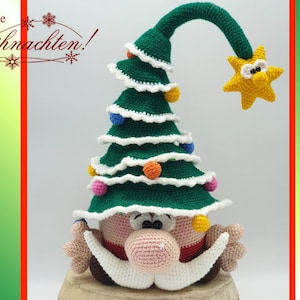 May include: A crocheted Christmas tree gnome with a green hat, white trim, and colorful ornaments. The gnome has a pink nose, white beard, and brown eyes. The gnome is sitting on a wooden base.