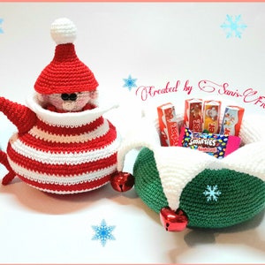 May include: Two crocheted Christmas gift baskets. One is shaped like a teapot with a red and white striped pattern and a small elf doll inside. The other is a green basket with white trim and red bells. Both baskets are filled with candy.