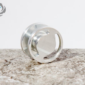 May include: A silver metal pulley with a circular design. The pulley has a groove for a rope or cable to run through.