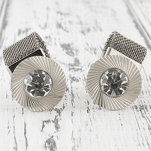May include: A pair of silver cufflinks with a mesh design and a clear rhinestone in the center of each cufflink.