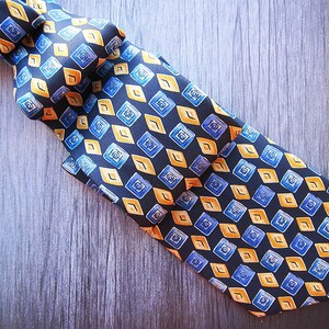 May include: A black silk tie with a geometric pattern of yellow and blue diamonds.