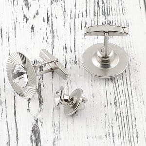 May include: Three silver cufflinks with clear crystal accents. One cufflink features a round design with a crystal in the center. Another cufflink features a rectangular design with a crystal in the center. The third cufflink features a round design with a crystal in the center.