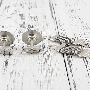 May include: Two silver cufflinks with a round, textured design and a silver chain with a textured design.