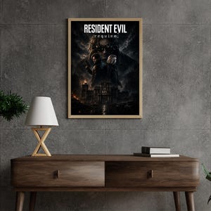 May include: A rectangular wall poster in a light wood frame featuring the text RESIDENT EVIL requiem. The artwork displays two figures standing back-to-back in front of a dark, gothic mansion under a stormy, cloud-filled sky with fiery orange accents.