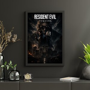 May include: A framed rectangular wall poster featuring the text RESIDENT EVIL requiem. The artwork displays two figures standing back-to-back in front of a dark, gothic building under a stormy sky, with a large, shadowy face looming above them.