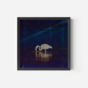 Puede incluir: Una impresión artística enmarcada que presenta una silueta de flamenco blanco en el agua. El fondo es azul oscuro con una textura sutil, sugiriendo una escena nocturna. El reflejo del flamenco es visible en el agua, creando una estética serena y minimalista.