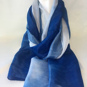 Peut inclure: Une écharpe en soie bleu et blanc ombrée. L'écharpe est drapé autour du cou d'un mannequin et est nouée en un nœud lâche.