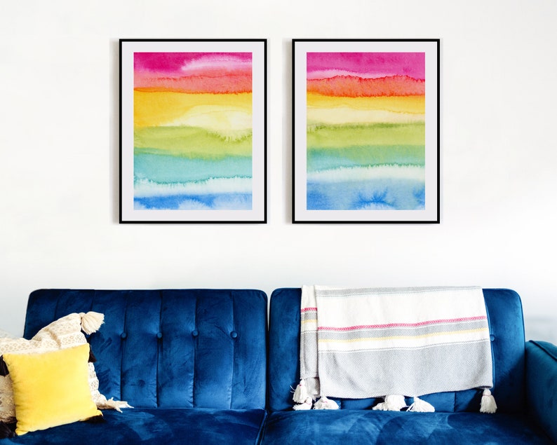 May include: Two framed abstract watercolour paintings with horizontal stripes of pink, orange, yellow, green, blue, and light blue.