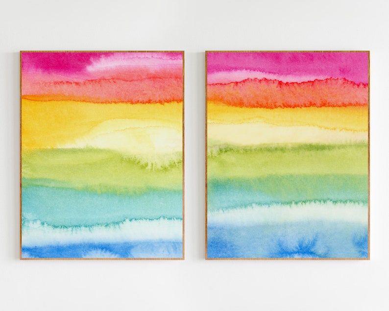 May include: Two framed abstract watercolour paintings with horizontal stripes of pink, orange, yellow, green, blue, and light blue.