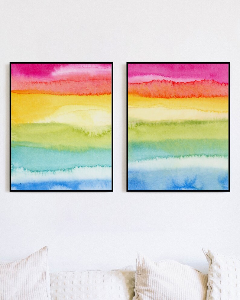 May include: Two framed abstract watercolour paintings with horizontal stripes of pink, orange, yellow, green, blue, and light blue.