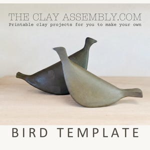 Puede incluir: Dos esculturas de aves estilizadas en gris oscuro mate y verde oliva apagado. El texto THE CLAY ASSEMBLY.COM, Printable clay projects for you to make your own, y BIRD TEMPLATE son visibles. Las aves tienen cuerpos lisos y curvos.