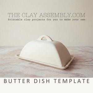 May include: A cream-colored ceramic butter dish with a rectangular base and a domed lid featuring a central arched handle. The text THE CLAY ASSEMBLY.COM Printable clay projects for you to make your own and BUTTER DISH TEMPLATE are visible.