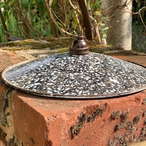 Puede incluir: Una pantalla de lámpara de cerámica moteada en blanco y negro con un casquillo de plástico marrón.