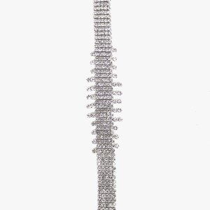 May include: A silver chain necklace with a long, rectangular pendant made of small, clear rhinestones. The pendant has a jagged, irregular shape.