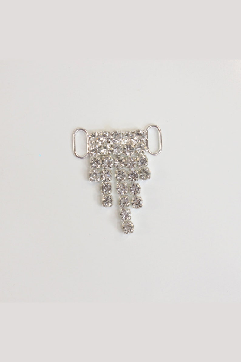 May include: Silver-toned metal bra strap extender with a teardrop-shaped design featuring a cascade of clear rhinestones.