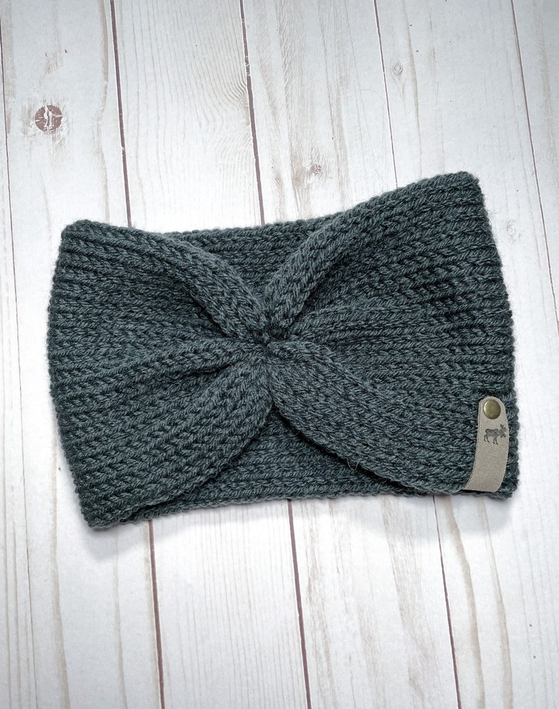 Peut inclure: Un bandeau en tricot gris avec une &eacute;tiquette en cuir marron orn&eacute;e d'un logo de  moose blanc.