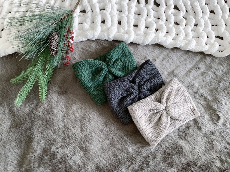Peut inclure: Trois bandeaux en tricot de couleur verte, grise et beige avec un n&oelig;ud nou&eacute;. Les bandeaux sont dispos&eacute;s sur une surface grise et duveteuse.