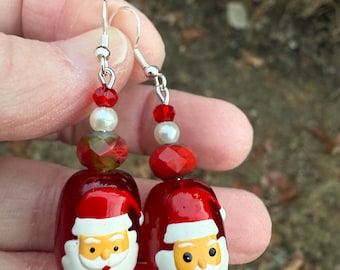 May include: Red and white Santa Claus face dangle earrings with silver hooks and red and white beads.