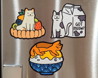 May include: Four refrigerator magnets featuring cartoon cats. One magnet shows a cat sitting on a fruit tart, another shows a cat sitting next to a carton of milk with the text "Got Meow?" printed on it, another shows a cat sitting in a bowl of ice cream, and the last magnet shows a cat sitting on a plate of food.
