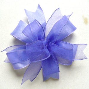 May include: A purple sheer ribbon bow with multiple layers and a ruffled edge.