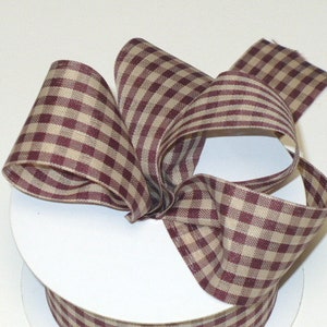 May include: A roll of brown and burgundy gingham ribbon. The ribbon is woven with a checkered pattern.