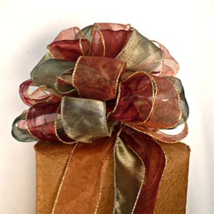 May include: A large, multi-colored bow made of sheer ribbon with gold accents. The bow is tied on top of a brown gift box.