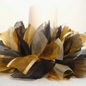 May include: A white candle sits on a bed of black and gold tulle, creating a festive centerpiece.