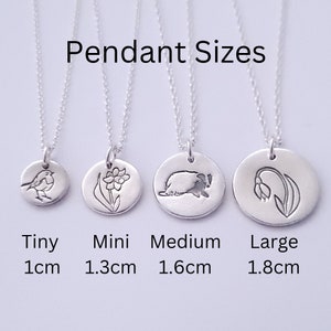 May include: Four silver pendant necklaces with different designs and sizes. The pendants are 1 cm, 1.3 cm, 1.6 cm, and 1.8 cm in diameter. The designs include a robin, a daffodil, a hedgehog, and a lily of the valley.