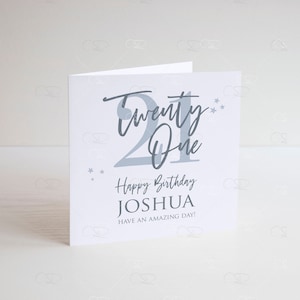 May include: A white card with a gray design that says "Twenty One" with stars. The card says "Happy Birthday Joshua Have an Amazing Day!"