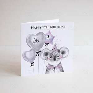 May include: A white card with the text "Happy 7th Birthday" and the name "Lily" written on a heart-shaped balloon. A koala wearing glasses and a party hat is holding a star-shaped balloon with the number "7" on it.