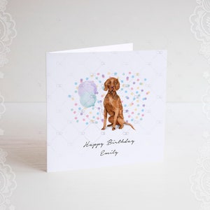 Pode incluir: Um cart&atilde;o de anivers&aacute;rio com uma ilustra&ccedil;&atilde;o em aquarela de um c&atilde;o marrom sentado em frente a um bal&atilde;o azul e roxo com confete. O cart&atilde;o diz "Feliz anivers&aacute;rio Emily".