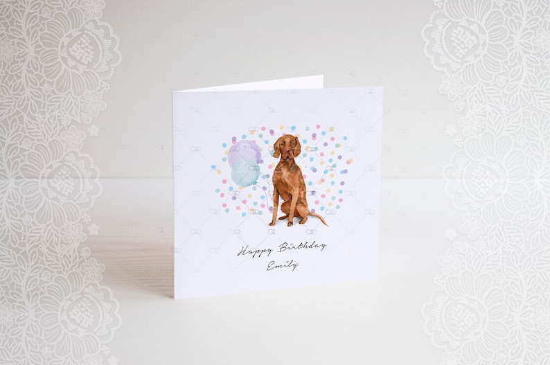 Pode incluir: Um cart&atilde;o de anivers&aacute;rio com uma ilustra&ccedil;&atilde;o em aquarela de um c&atilde;o marrom sentado em frente a um bal&atilde;o azul e roxo com confete. O cart&atilde;o diz "Feliz anivers&aacute;rio Emily".
