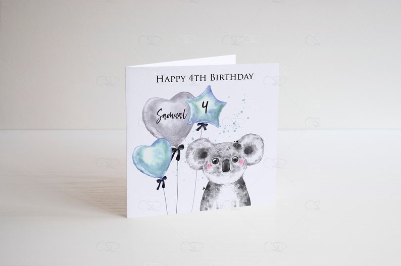 May include: A white card with a watercolor illustration of a koala holding blue and gray balloons. The balloons have the text "Samuel" and the number "4" on them. The card reads "Happy 4th Birthday".