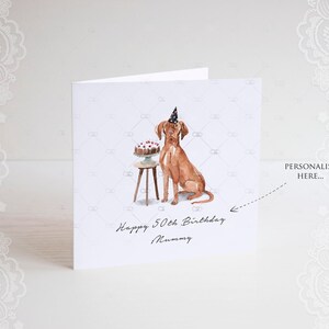 Pode incluir: Um cart&atilde;o de anivers&aacute;rio personalizado com um c&atilde;o castanho a usar um chap&eacute;u de festa e sentado ao lado de um bolo numa mesa pequena. O cart&atilde;o diz "Happy 50th Birthday Mummy".