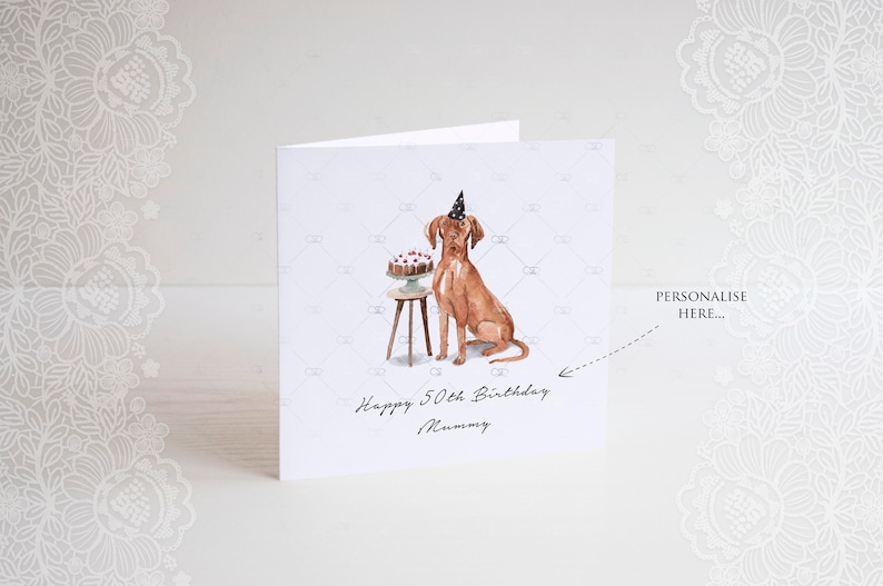 Pode incluir: Um cart&atilde;o de anivers&aacute;rio personalizado com um c&atilde;o castanho a usar um chap&eacute;u de festa e sentado ao lado de um bolo numa mesa pequena. O cart&atilde;o diz "Happy 50th Birthday Mummy".