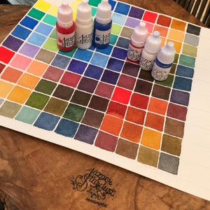 May include: A watercolor paint chart with 64 color swatches arranged in a grid. The chart is labeled "Jazper Stardust Handmade". There are five small bottles of watercolor paint on the chart, labeled "Jazper Stardust".