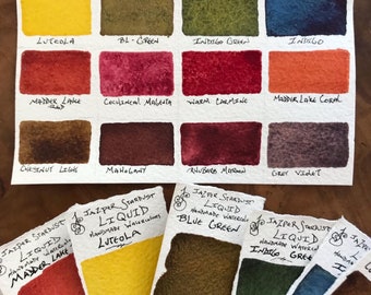 May include: A set of 12 handmade liquid watercolors in a variety of colors, including yellow, green, red, brown, and purple. The watercolors are labeled with their names, such as "Luteola", "Indigo Green", and "Madder Lake". The set is part of the "Akoustik Series #1" and is made by Jazper Stardust.
