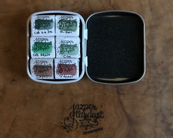 May include: A tin of six watercolor paints in a metal case. The paints are labeled "Jazper Stardust" and include the colors "Cob 64 DK", "B-Roor", "Cob Green", "CGE", "Capot", and "Pheart".