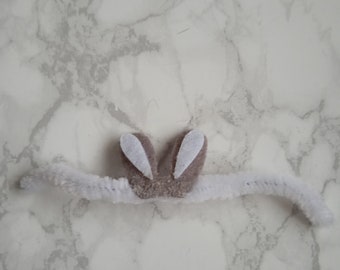 May include: A white headband with gray bunny ears. The ears have white tips.