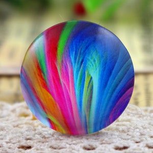 May include: A round, colorful, abstract design cabochon with swirls of blue, green, pink, orange, and yellow.