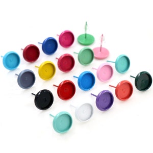 May include: Assortment of 18 colourful round earring settings with a silver post. The settings are in various colours including red, blue, green, yellow, black, white, and purple.