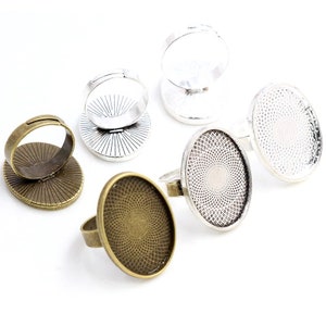 May include: Set of six oval-shaped ring blanks, three in silver and three in bronze. Each blank has a decorative pattern on the surface. The blanks are designed to be used for creating custom rings.
