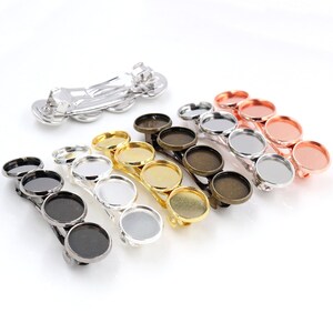 May include: Six hair clips with different colored metal frames and clear round glass or plastic inserts. The clips are designed to hold charms or other embellishments.