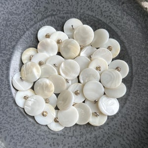 May include: A bowl of white mother of pearl buttons with silver shanks.