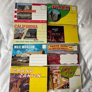 May include: Six vintage postcards featuring scenic views of the United States. The postcards are yellow, blue, and green with images of Mount Rushmore, Utah, California, Reno, Arizona, and New Orleans.