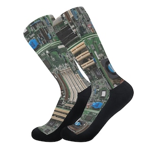 May include: Two knee-high socks with a printed design of a computer motherboard. The socks have black toes and heels, with the motherboard design in green, blue, and beige. A unique and tech-inspired accessory.
