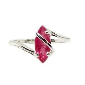Puede incluir: Un anillo de plata con una gema roja vibrante en forma de marquesa. La gema está envuelta con una banda de plata, creando un diseño único y elegante. El anillo está sobre un fondo blanco.