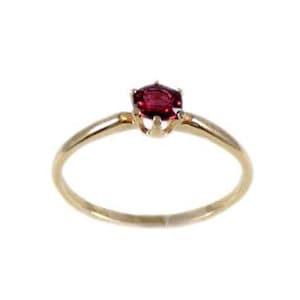 May include: A simple gold band ring with a single red gemstone set in a four-prong setting.